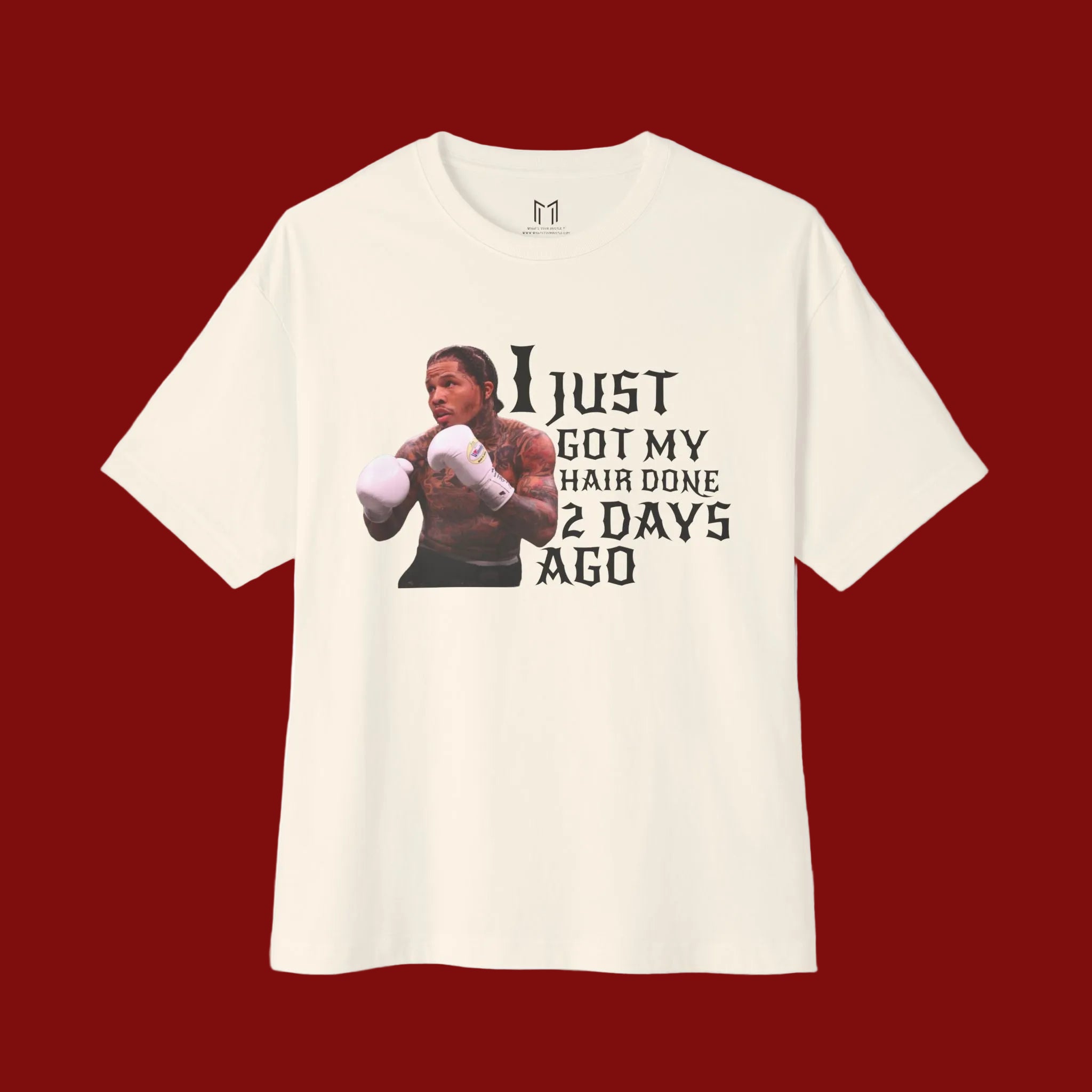An off-white short-sleeve t-shirt with a graphic print of a boxer and the text 'I JUST GOT MY HAIR DONE 2 DAYS AGO' in black, displayed on a clean white background.